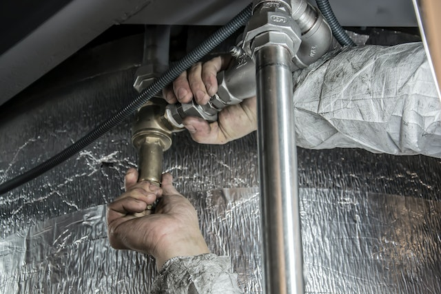 Plumber repairing pipes under a sink – professional plumbing services for leak repairs and maintenance.