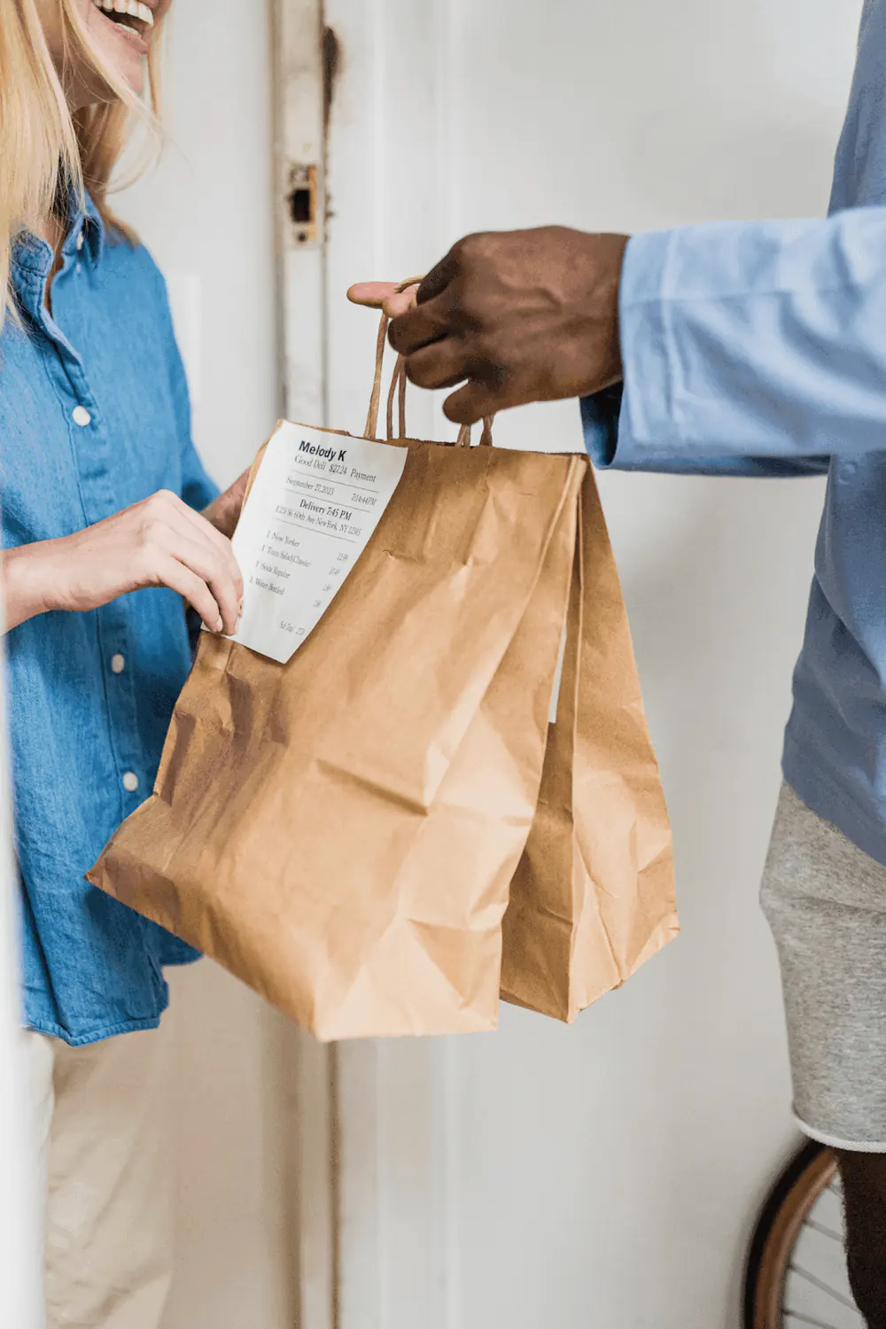 Customer receiving a food delivery with a printed receipt attached to the paper bag, showcasing how receipts are used in everyday transactions, unlike invoices.