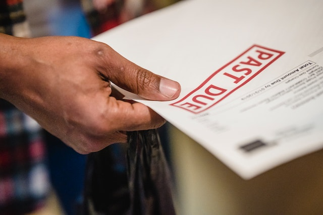 A person holding a document marked with 'PAST DUE,' indicating a late payment notice or overdue bill.
