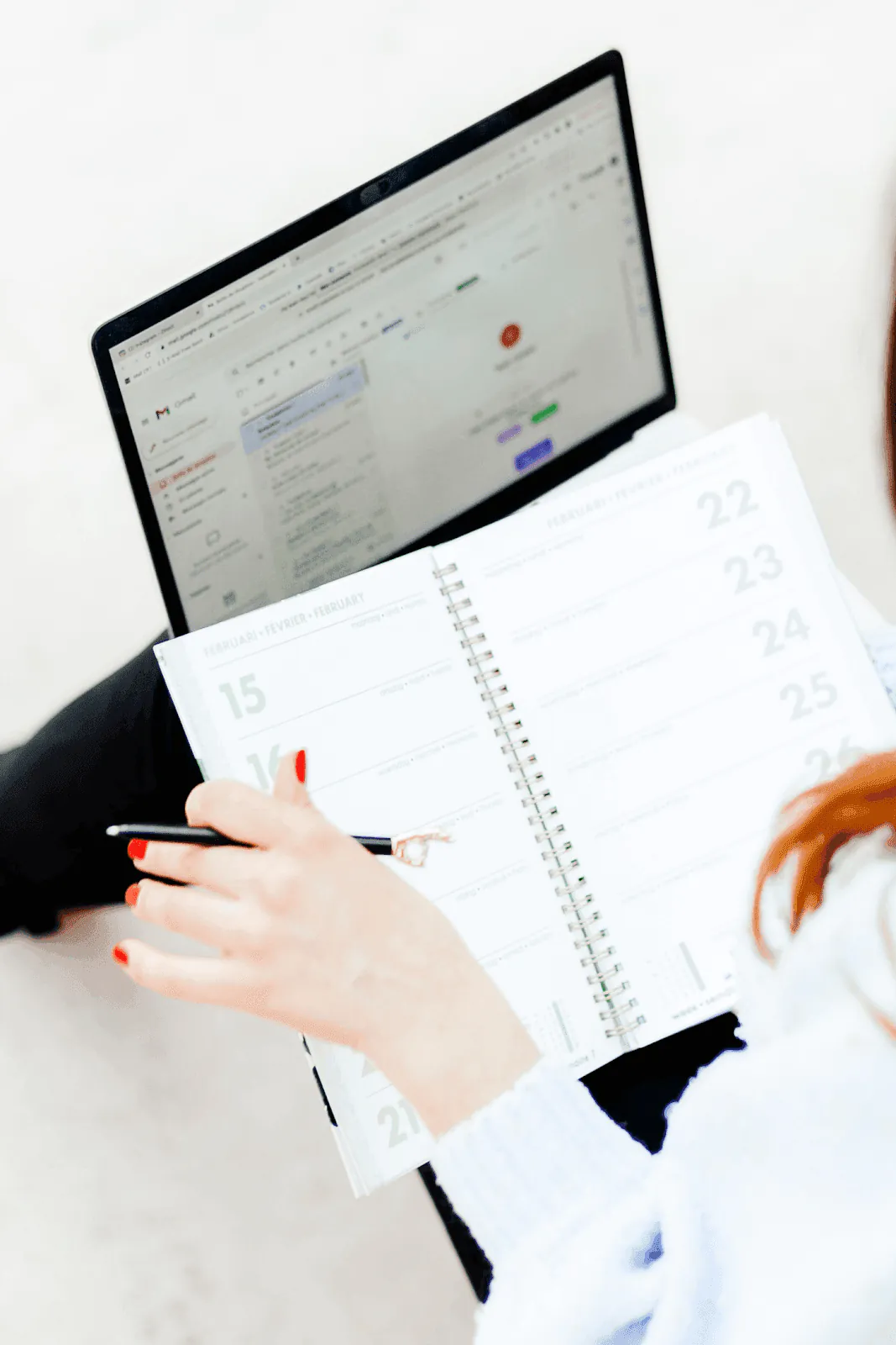 Person reviewing schedule in a planner while composing an invoice email on a laptop, How to write an invoice email with a free template for businesses and freelancers.