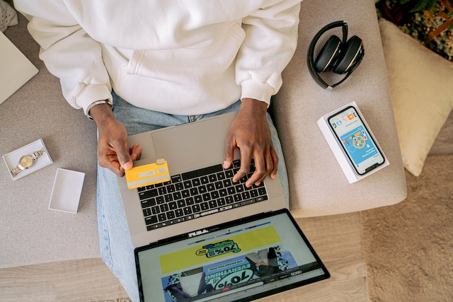 Person making an online payment using a credit card and laptop, settling a past due invoice while managing finances from home.