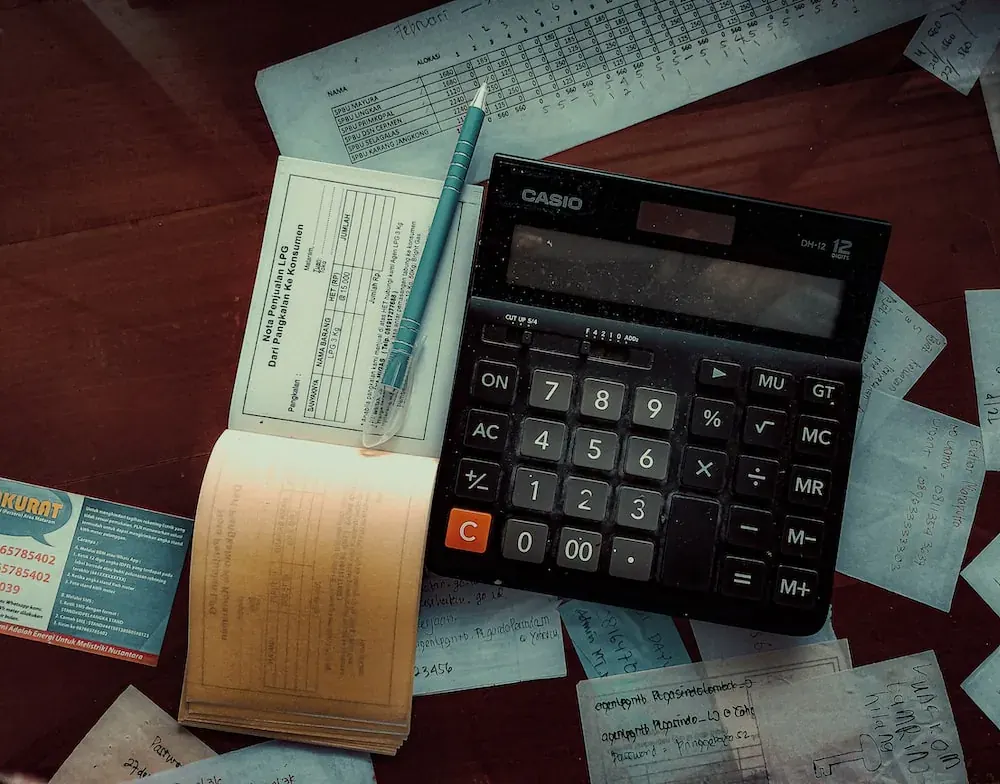 Plumbing invoice, calculator, and pen on a desk, essential tools for plumbers to manage billing and invoicing efficiently.