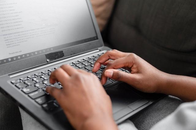 Close-up of a person typing on a laptop keyboard, emphasizing the role of technology in managing contract lifecycle management (CLM) stages and digital contract management.