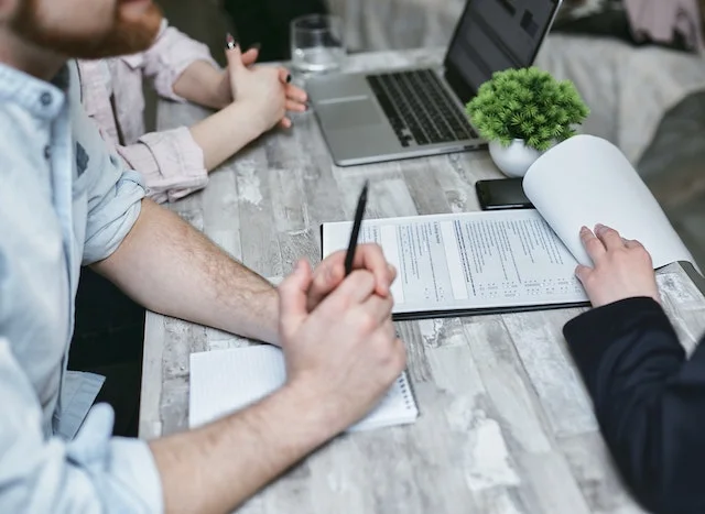 Business professionals reviewing and discussing SaaS contract documents during a meeting