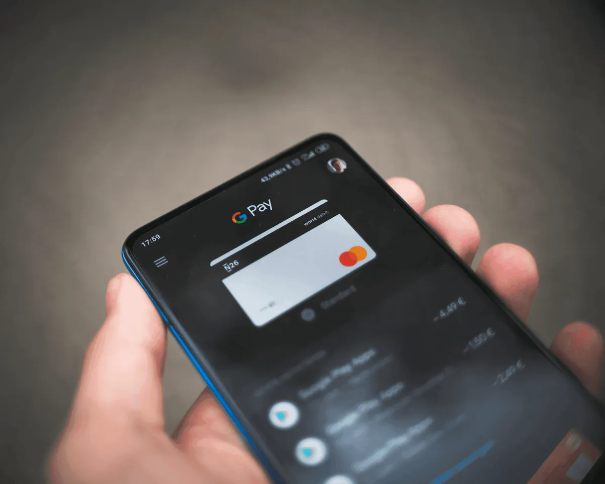 Close-up of a person holding a smartphone with a digital payment app open, displaying a virtual credit card. This illustrates the transition from invoice to payment, highlighting modern financial transactions and digital invoicing.