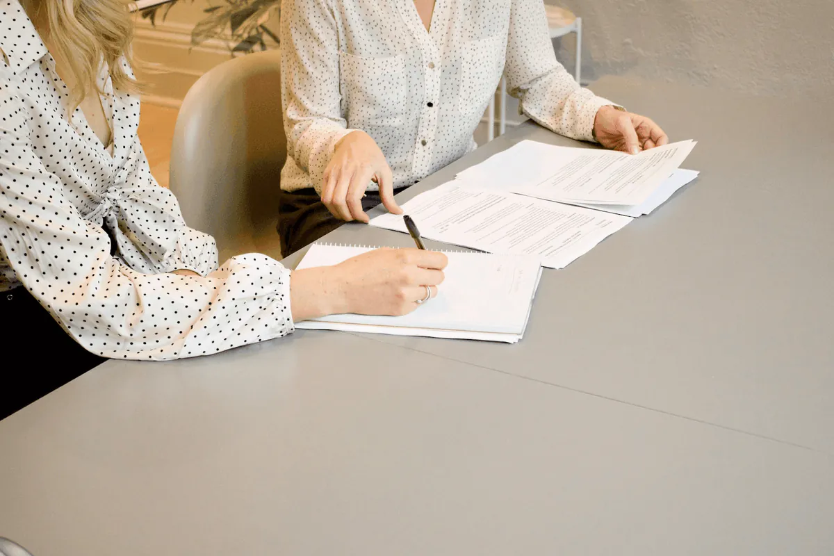 Two business professionals reviewing and discussing financial documents at a desk, representing the process of creating a quote versus issuing an invoice in business transactions.