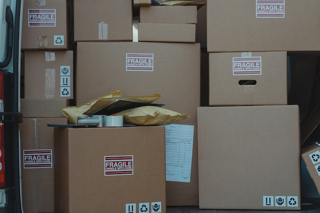Stack of fragile-labeled shipping boxes with a visible packing list — illustrating the role of a proforma invoice in international shipping and customs documentation.